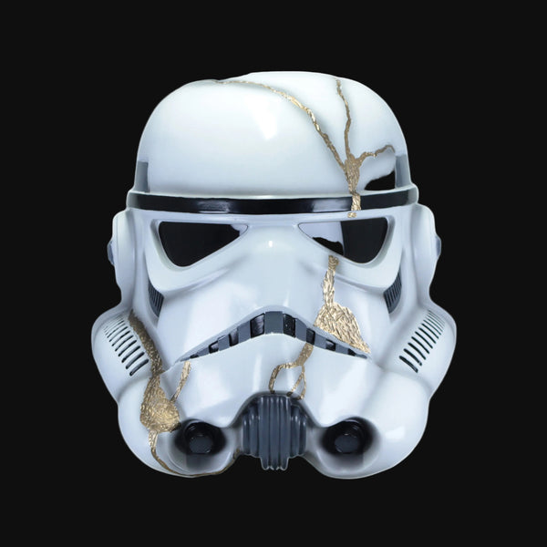 A white stormtrooper helmet with gold crackle detailing and black visor areas.